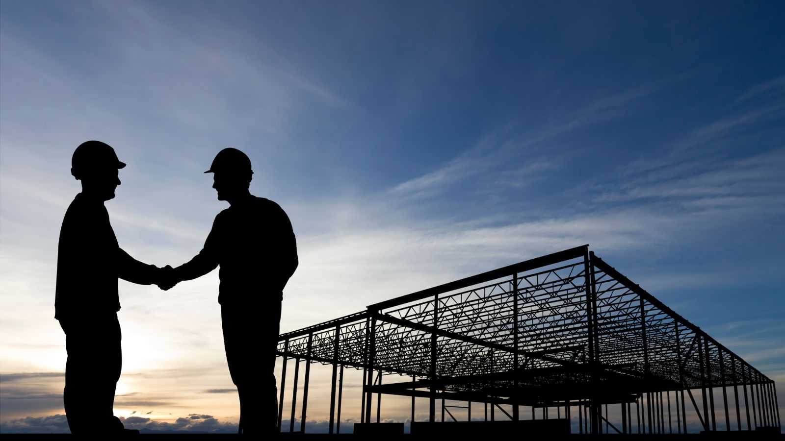 silhouette of two men shaking hands at job site