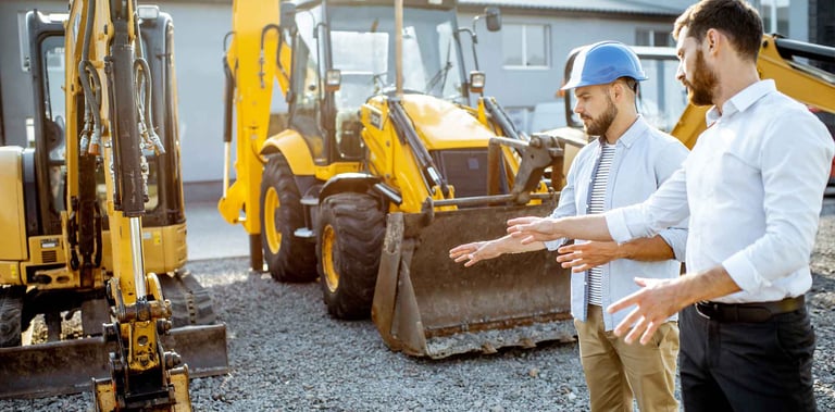 business professionals looking at construction equipment in a lot