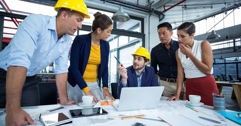 construction admin workers discussing a project around a laptop