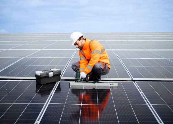 solar energy worker installing photovoltaic panels on the roof